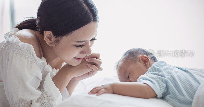 Close up portrait of beautiful young asian mother with her newborn baby, copy space with bed in the hospital background. Healthcare and medical family love lifestyle nursery motherâs day concept